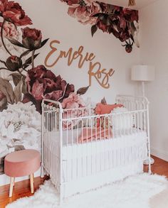 a white crib in front of a floral wall mural