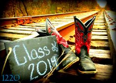 a pair of cowboy boots sitting on top of a train track next to a sign