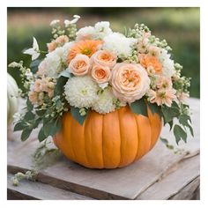 a pumpkin filled with white and orange flowers