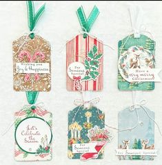 four tags with christmas designs on them are hanging from twine string and decorated with ribbons