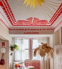 a living room filled with furniture and a large sun painted on the ceiling above it