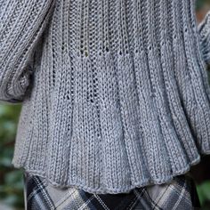 the back of a woman's sweater with an argyle plaid skirt and black boots