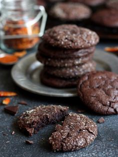 three chocolate cookies on a plate with one broken in half