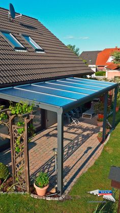 an outdoor patio with a blue cover and potted plants on the side of it