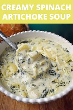 creamy spinach artichoke soup in a white bowl with a spoon inside it