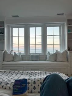 a bedroom with a large window seat next to a bed in front of a book shelf