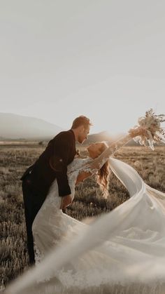 a bride and groom kissing in an open field with the sun shining down on them