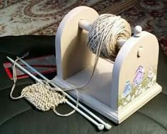 a spool of thread and two knitting needles are sitting on top of a chair