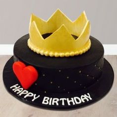 a birthday cake with a crown on top and a red heart in the middle is sitting on a table