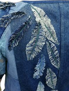 the back of a jean jacket with embroidered leaves on it