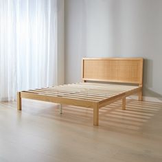 a wooden bed frame sitting on top of a hard wood floor next to a window