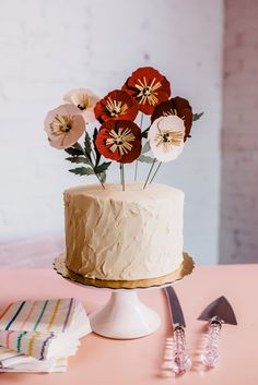 there is a cake with flowers on it and two forks next to the cake plate