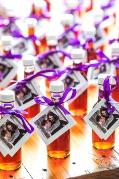 honey bottles with photos tied to them and purple ribbons on the top, sitting on a wooden table