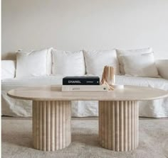 a white couch sitting next to a table in front of a book on top of it