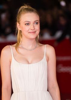 a woman in a white dress is posing for the camera with her hair pulled back