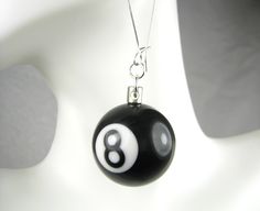 a black and white ball with a number eight on it hanging from a silver chain