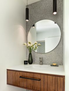 a bathroom sink with a mirror above it and flowers in a vase on the counter