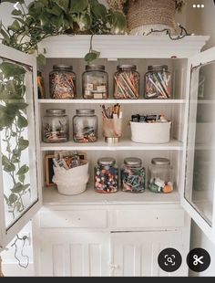 an open cabinet with many jars and pencils in them on top of the shelves