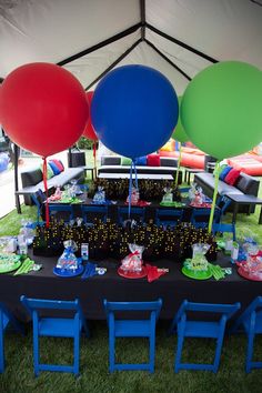 the table is set up with balloons and other items for an outdoor party or celebration