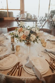 the table is set with white and gold plates, silverware, and floral centerpieces