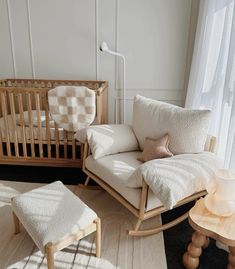 a baby's room with a rocking chair, crib and table in it