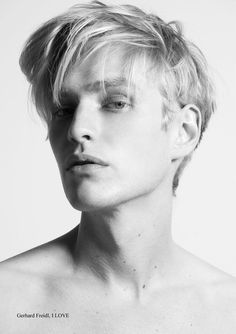 black and white photograph of a man with blonde hair looking off to the side while wearing no shirt