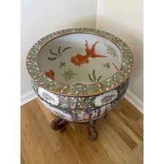 a decorative bowl sitting on top of a wooden table next to a wall and hardwood floor