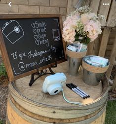 a sign that is on top of a barrel with some flowers in the buckets