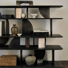 a shelf with vases, books and other decorative items on it in a room