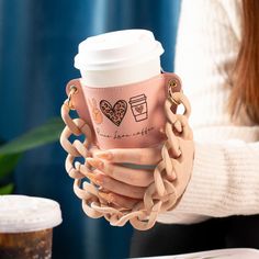 a woman holding a coffee cup in her hand with chains around the sleeve and chain at the wrist