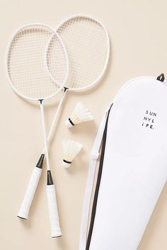 two tennis racquets and a shuttle on a beige background with the words sun my life written on it