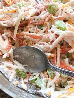 a large salad is in a glass bowl with a spoon