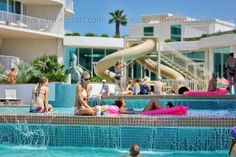 people are sitting in the swimming pool at an apartment complex with slides and water features