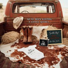 an old red truck with cowboy boots and other items on the bed in front of it