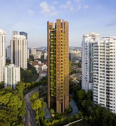 an aerial view of a tall building in the middle of a city with lots of trees growing on it