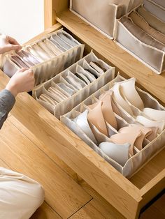 a drawer with several pairs of shoes in it and someone reaching for the one shoe