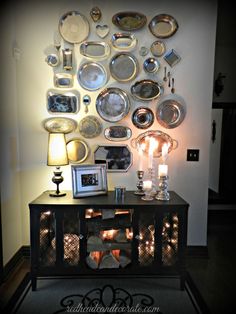 a table with candles and plates on it in front of a wall mounted art piece