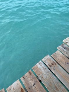 the water is very blue and green with some wooden planks in front of it