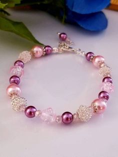 A pink and purple pearl bracelet made glass beads and glass pearls. Measures 8" in length. Elegant Pink Crystal And Pearl Bracelet, Elegant Pink Pearl Crystal Bracelet, Pink Beaded Pearl Bracelet For Wedding, Purple Beaded Bracelets For Wedding, Elegant Adjustable Pink Rosary Bracelet, Elegant Pink Rosary Bracelet With Round Beads, Elegant Pink Adjustable Rosary Bracelet, Elegant Pink Rosary Bracelet For Wedding, Wedding Beaded Pink Pearl Bracelet