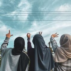 three people standing in front of power lines with their hands up