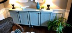 a living room with wicker furniture and blue vases on top of the cabinet