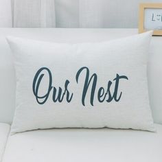 a white couch with a pillow that says our nest on it and a clock in the background