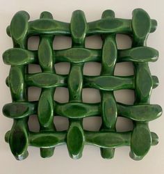 a close up of a green tile design on a white wall in the shape of a basket