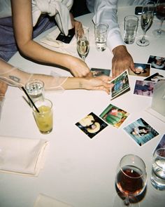 people sitting at a table with pictures and drinks on the table, all holding hands