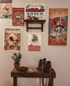 there are posters on the wall above a wooden table with a cowboy boot sitting on it