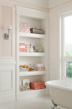 a white bath tub sitting in a bathroom next to a window filled with pink towels