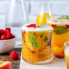 two glasses filled with different types of drinks and fruit next to each other on a table