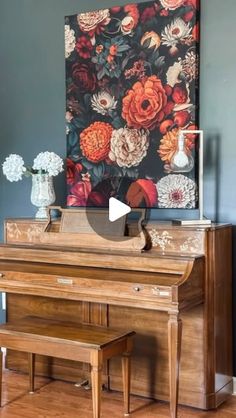 a piano sitting in front of a painting on the wall next to a vase with flowers