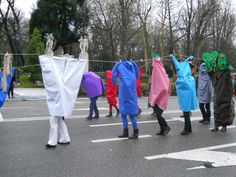 several people in costumes are walking down the street with clothes hanging on a line above them