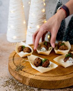 a person reaching for some food on top of a wooden tray with other foods in it